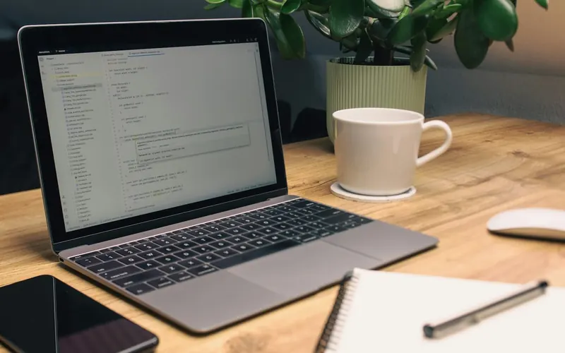 Ordinateur portable, carnet, téléphone et tasse sur un bureau