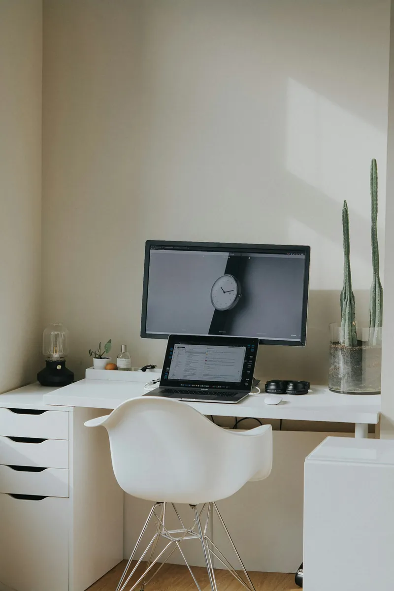 Full view of a white desk with a laptop, monitor, chair and cactus